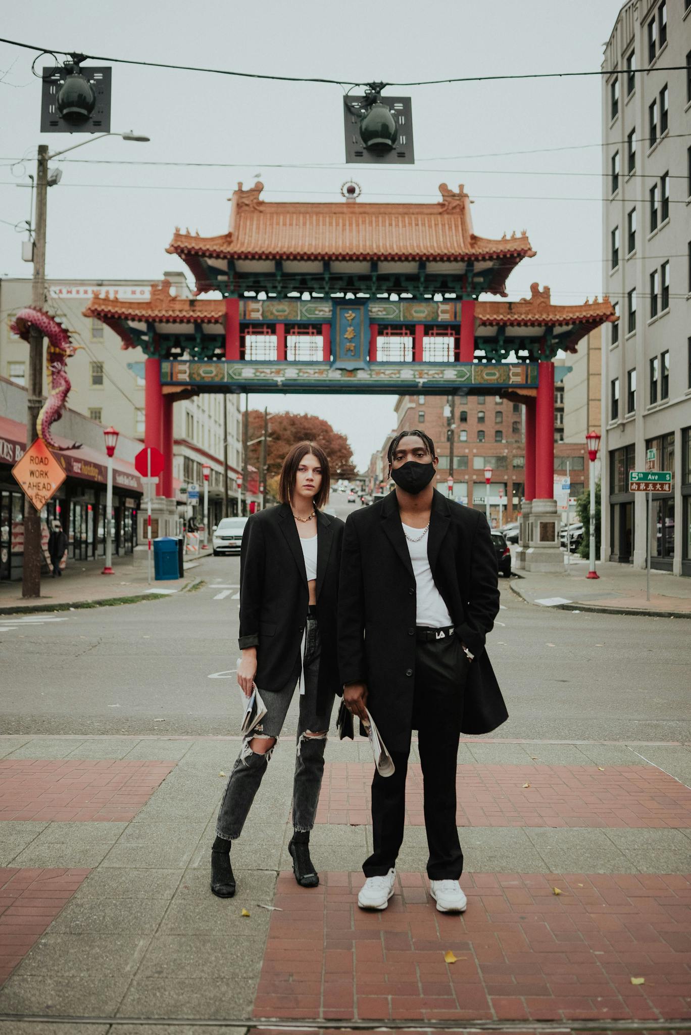 Fashionable young multiracial couple relaxing on city street during coronavirus